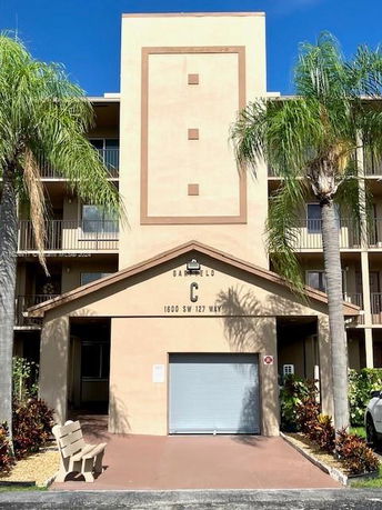 Front view of a multi-story building with balconies and palm trees.