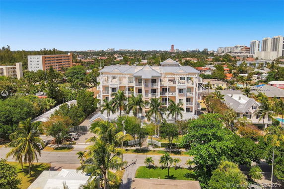 Front view of a multi-story building with balconies and palm trees in the foreground.