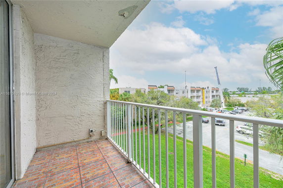 View from a balcony overlooking parking area and apartment buildings.