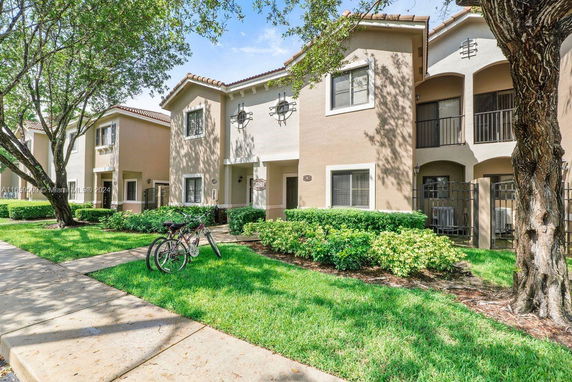 Front view of a two-story residential building with a small front porch and green landscaping.