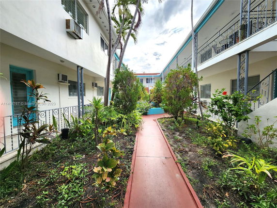 Outdoor view of an apartment complex with a garden and walkway between two buildings.