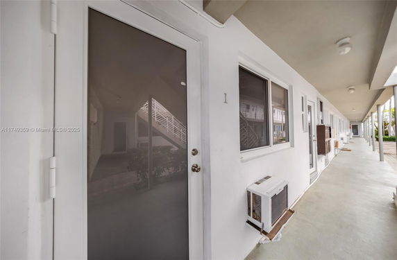 Outdoor corridor of a building with multiple doors and windows.