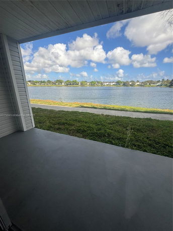 Wide angle view of a lake and distant buildings from a covered porch.