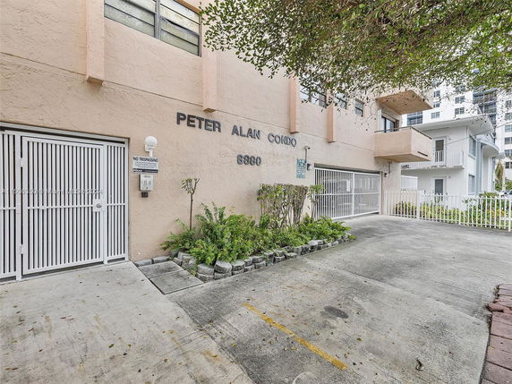 Front view of a condo building with gated entrances and a small garden area.