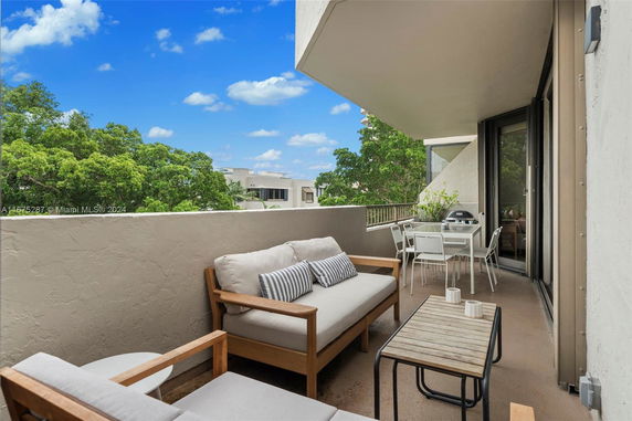 Balcony view with outdoor seating and trees in the background