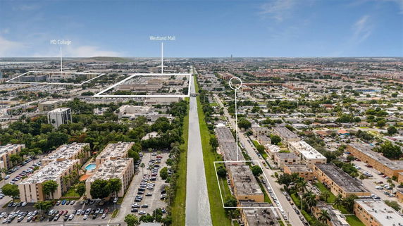 Wide aerial view of a cityscape including buildings, roads, and a canal.
