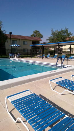 Outdoor swimming pool area with loungers and umbrellas.