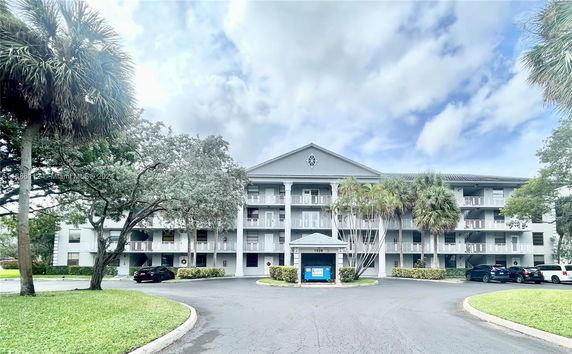 Front view of a multi-story residential building with balconies and a driveway.