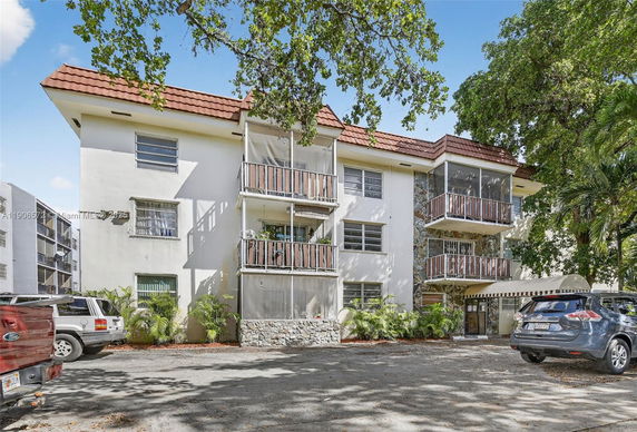 Front view of a three-story residential building with balconies and a tiled roof.