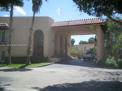 Front view of a large house with a covered driveway and arched entryway.