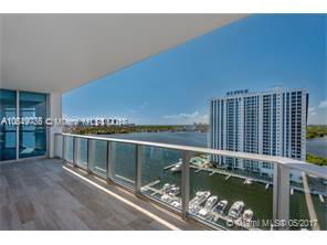 Panoramic view from a balcony overlooking a large body of water and nearby high-rise buildings.