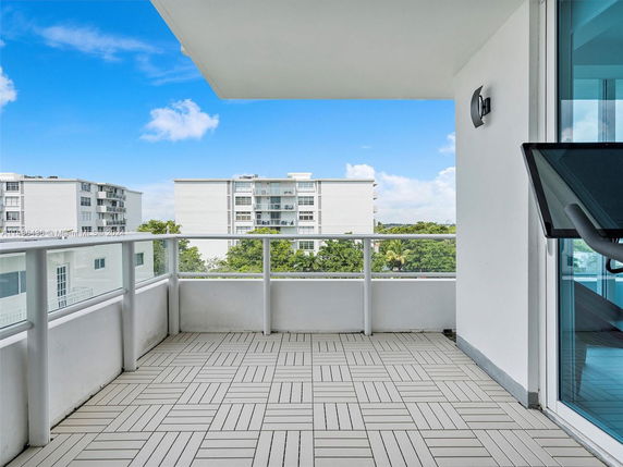 Balcony view overlooking apartment buildings and a clear blue sky.