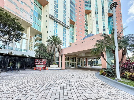 Front view of a multi-story building with a covered entrance and decorative landscaping.