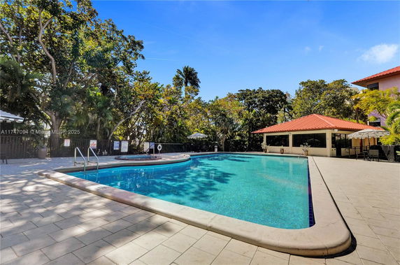 Outdoor swimming pool with surrounding trees and patio area.