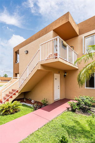 Front view of a two-story building with exterior stairs and white railing.