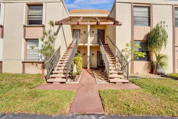 Front view of a two-story building with an external staircase and beige walls.