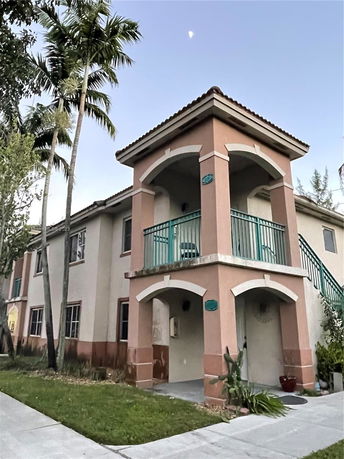 Front view of a two-story building with arches and a balcony.