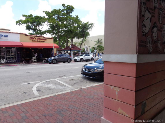 Street view of a Cuban bar and cocina with outdoor seating and a few parked cars.