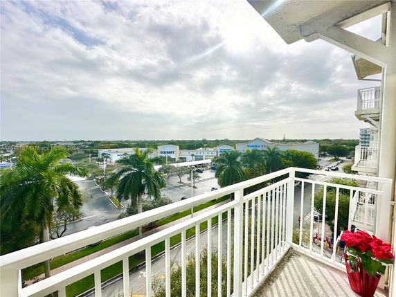 Panoramic view from a balcony overlooking a shopping area and palm trees.