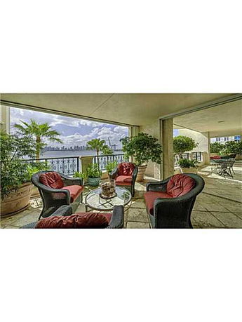 Covered outdoor seating area with a wide view of water and distant skyline.