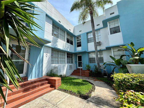 Front view of a blue and white two-story building with steps leading to the entrance.