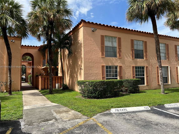 Front view of a two-story building with arched entrance and palm trees.