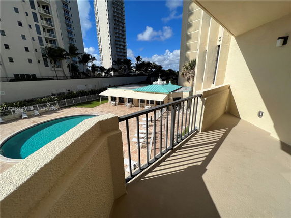 View from a high-rise balcony overlooking a pool area and adjacent tall buildings.