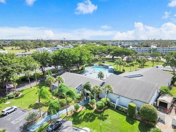 Aerial view of residential buildings surrounded by trees and a swimming pool.
