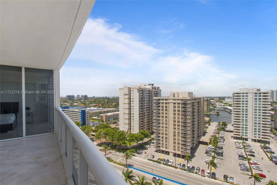 View from a high-rise balcony overlooking cityscape with apartment buildings and parking areas.