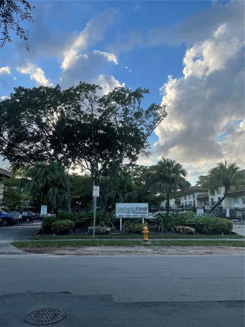 Front view of a residential building complex with trees and signage.