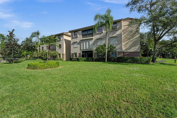 Exterior view of a three-story residential building with a manicured lawn in front.
