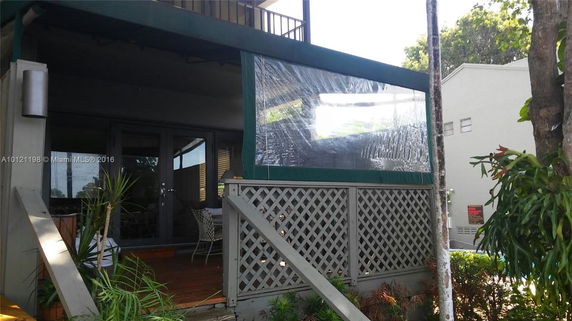Front view of an outdoor area with a covered porch and lattice railing.