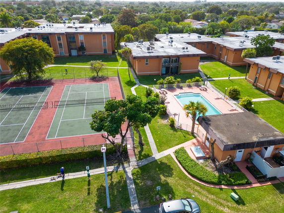 Aerial view of residential complex with swimming pool and tennis court.