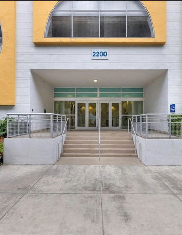 Front view of a building entrance with stairs and railings.