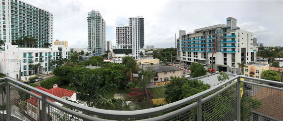 Panoramic view of a cityscape with tall buildings and lush greenery.