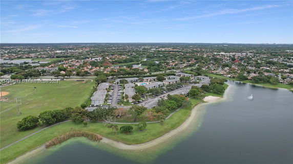 Aerial view of a residential area with a lake and green spaces.