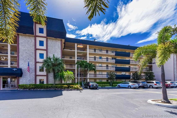 Front view of a multi-story residential building with balconies and parking area.