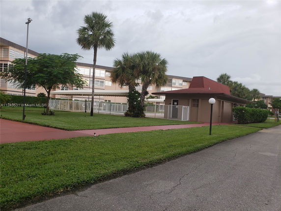 View of a building complex with a small structure and palm trees.