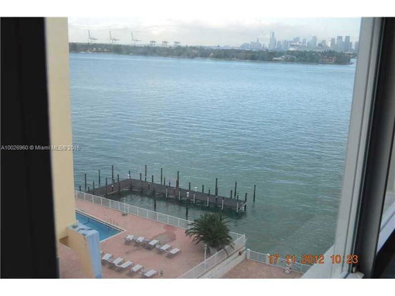 View from a building overlooking a waterfront with a dock and city skyline in the distance.
