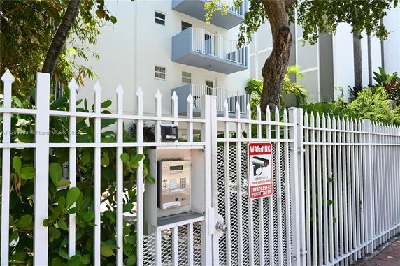 Front view of a multi-story building with balconies and secure entrance gate.