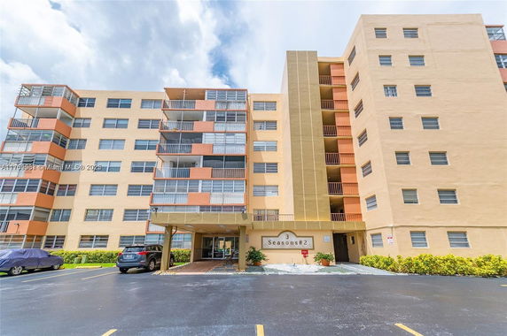Front view of a multi-story apartment building with balconies and a covered entrance.