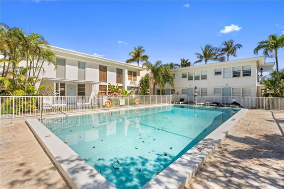Outdoor swimming pool with a white building in the background.