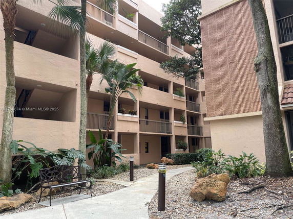 Front view of a multi-story residential building with balconies and a landscaped pathway.