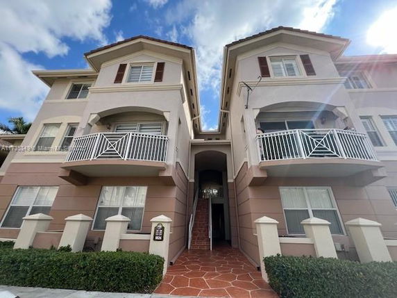 Front view of a multi-story residential building with balconies and brown shutters.