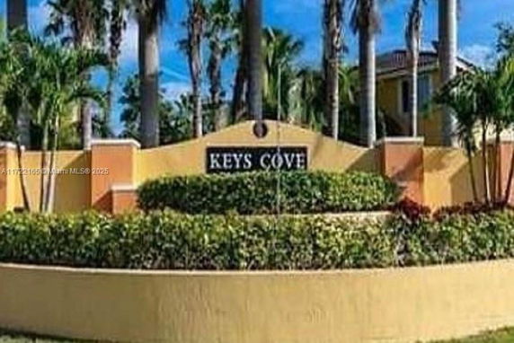 Entrance view of Keys Cove residential area with a sign and landscaping.