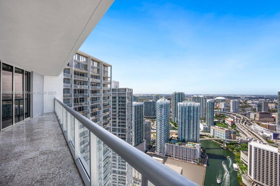 Panoramic view from a high-rise building balcony over a cityscape with skyscrapers and a river.