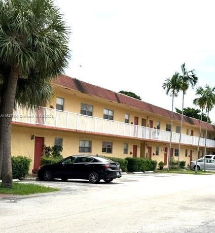 Front view of a two-story residential building with a row of doors and windows, and a balcony.