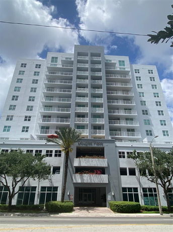 Front view of a multi-story building with balconies and landscaping.