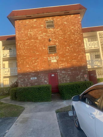 Front view of a multi-story brick building with a red roof and an entrance door.