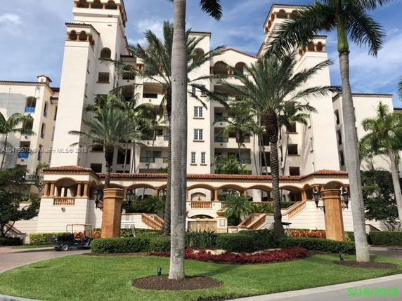 Front view of a multi-story building with arches and palm trees.